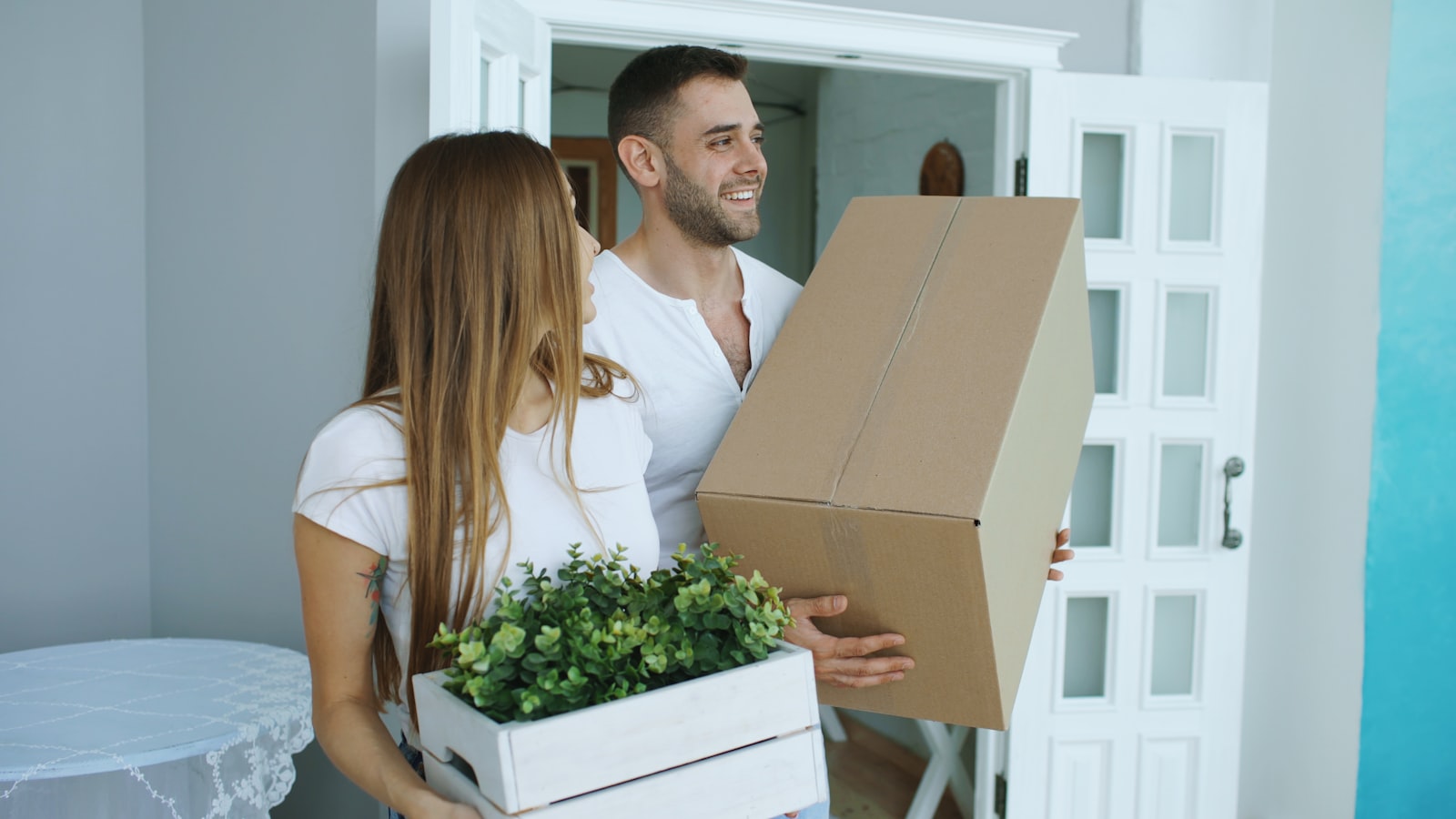 Couple carrying moving boxes into a bright new home